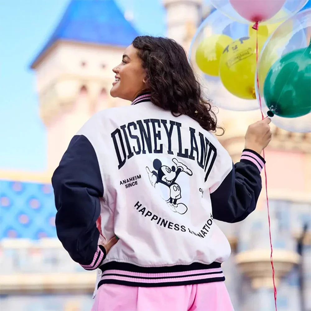 A girl wearing a Disneyland mickey mouse varsity jacket with balloons in the background