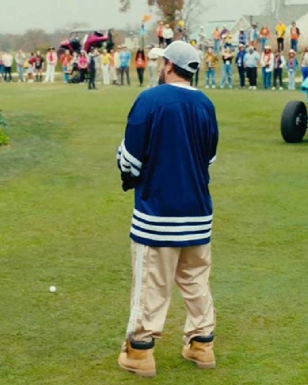 Person in a blue sweater with white stripes on a grassy field, surrounded by spectators.