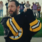 Man holding a black and yellow sports jersey with a logo, with people in the background.