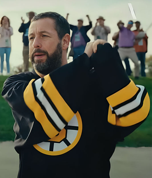 Man holding a black and yellow sports jersey with a logo, with people in the background.