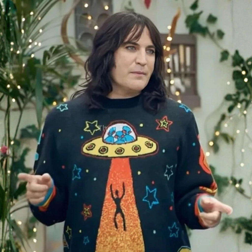 Person wearing a sweater with a UFO design in an indoor setting with plants and lights.