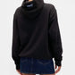 Person wearing a black hoodie with a logo on the back, standing against a white background