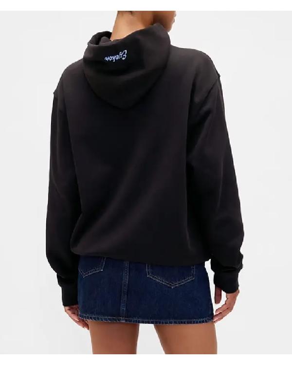 Person wearing a black hoodie with a logo on the back, standing against a white background