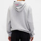Person wearing a gray hoodie with a logo on the back against a white background