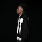 Person wearing a black hoodie with white designs on a black background