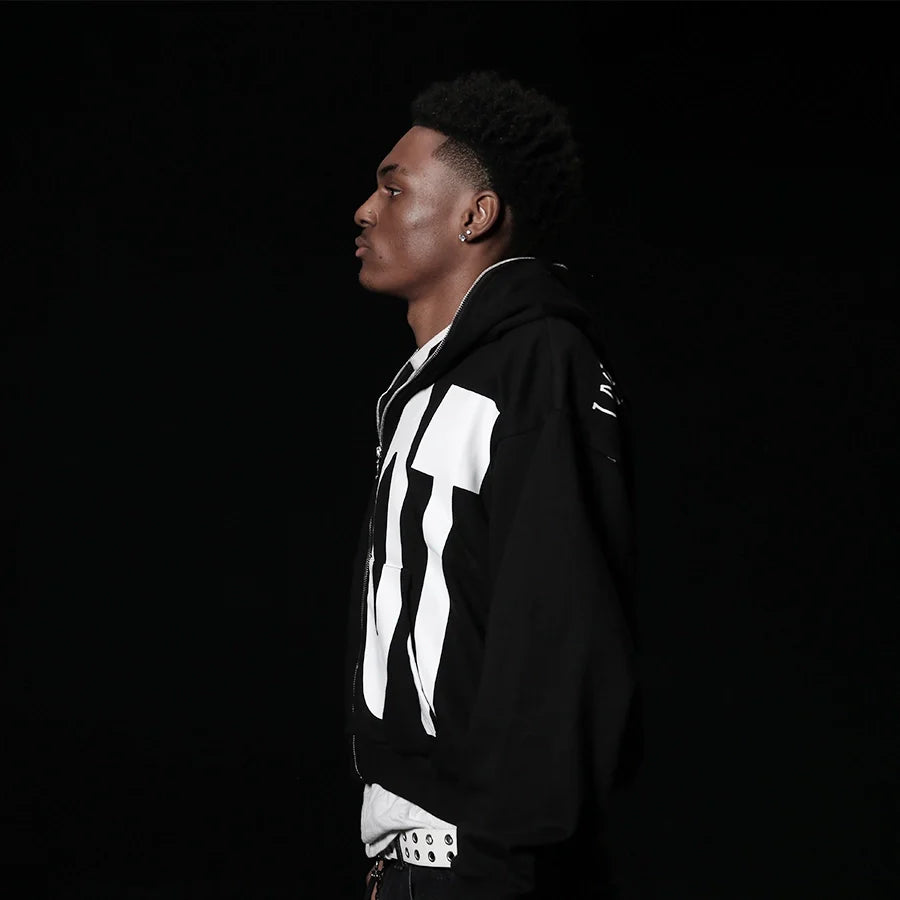 Person wearing a black hoodie with white designs on a black background