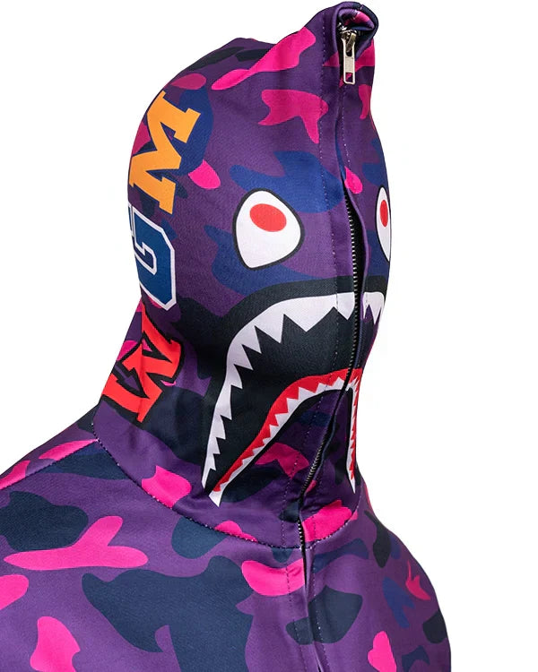 Close-up detail of the shark face graphic on the hood of a violet, pink, and navy camouflage zip-up hoodie.