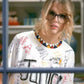 Taylor Swift wearing a white t-shirt with various writings and graphics in an indoor setting.