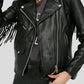 Person wearing a black leather jacket with fringe details on a plain background