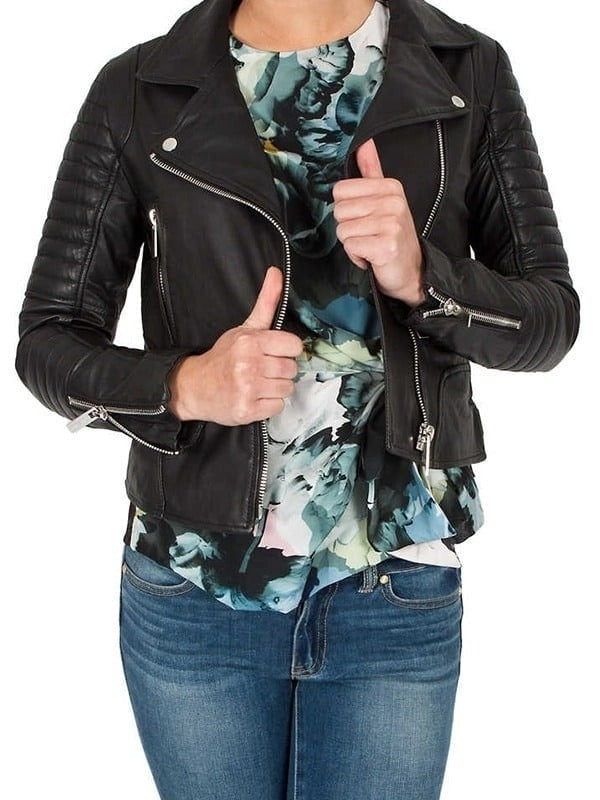 Person wearing a black leather jacket over a floral top and jeans on a white background