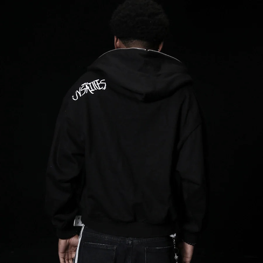 Person wearing a black hoodie with 'UNSTABLE' logo on the back against a dark background